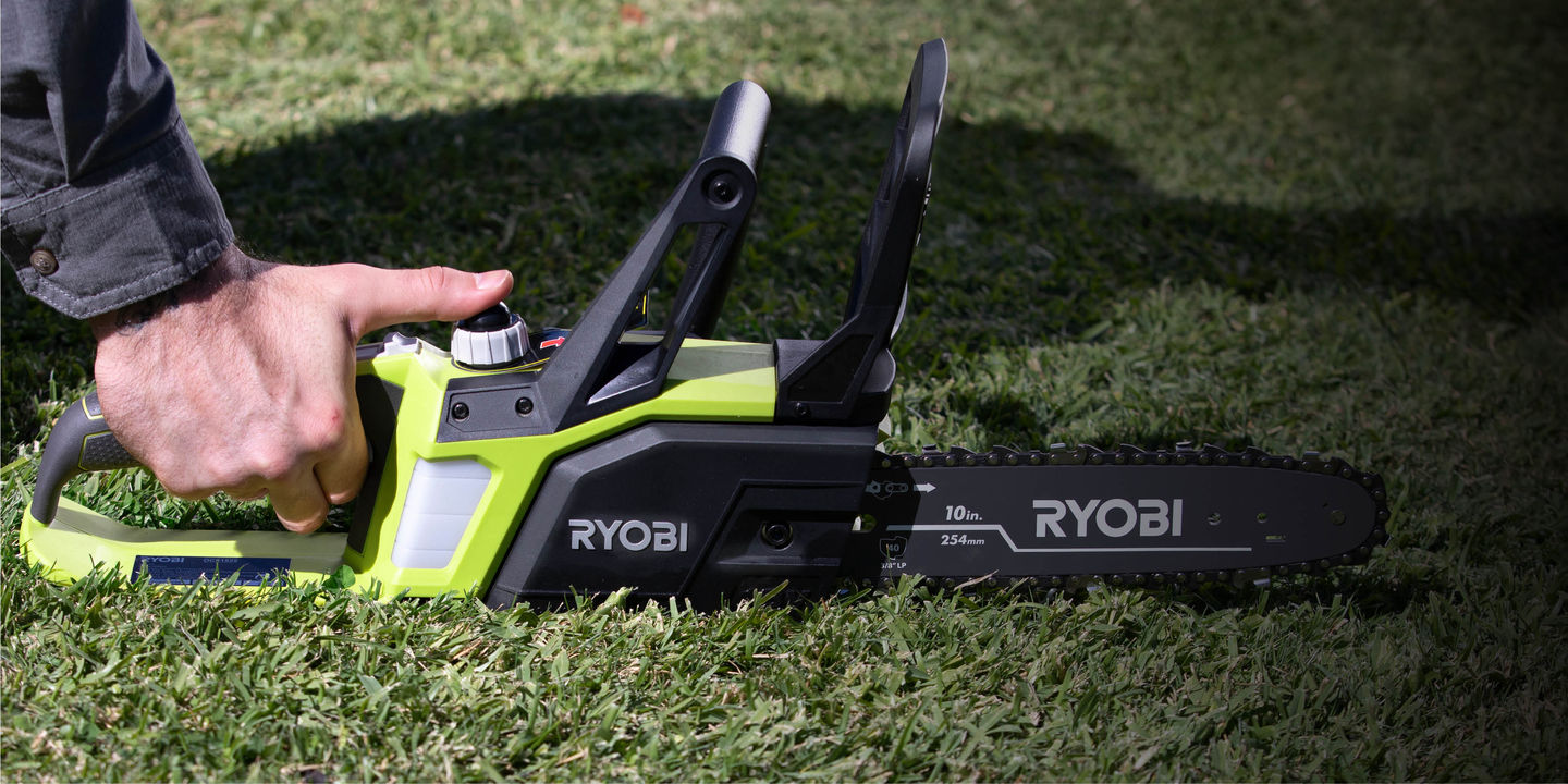 A Ryobi chainsaw sitting on the grass for oiling
