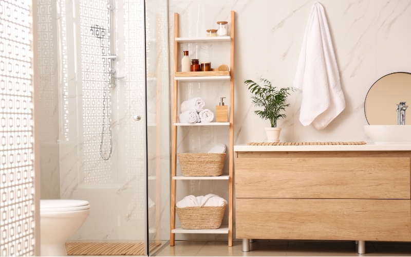 A wooden, DIY blanket ladder used in a bathroom to store towels and beauty products