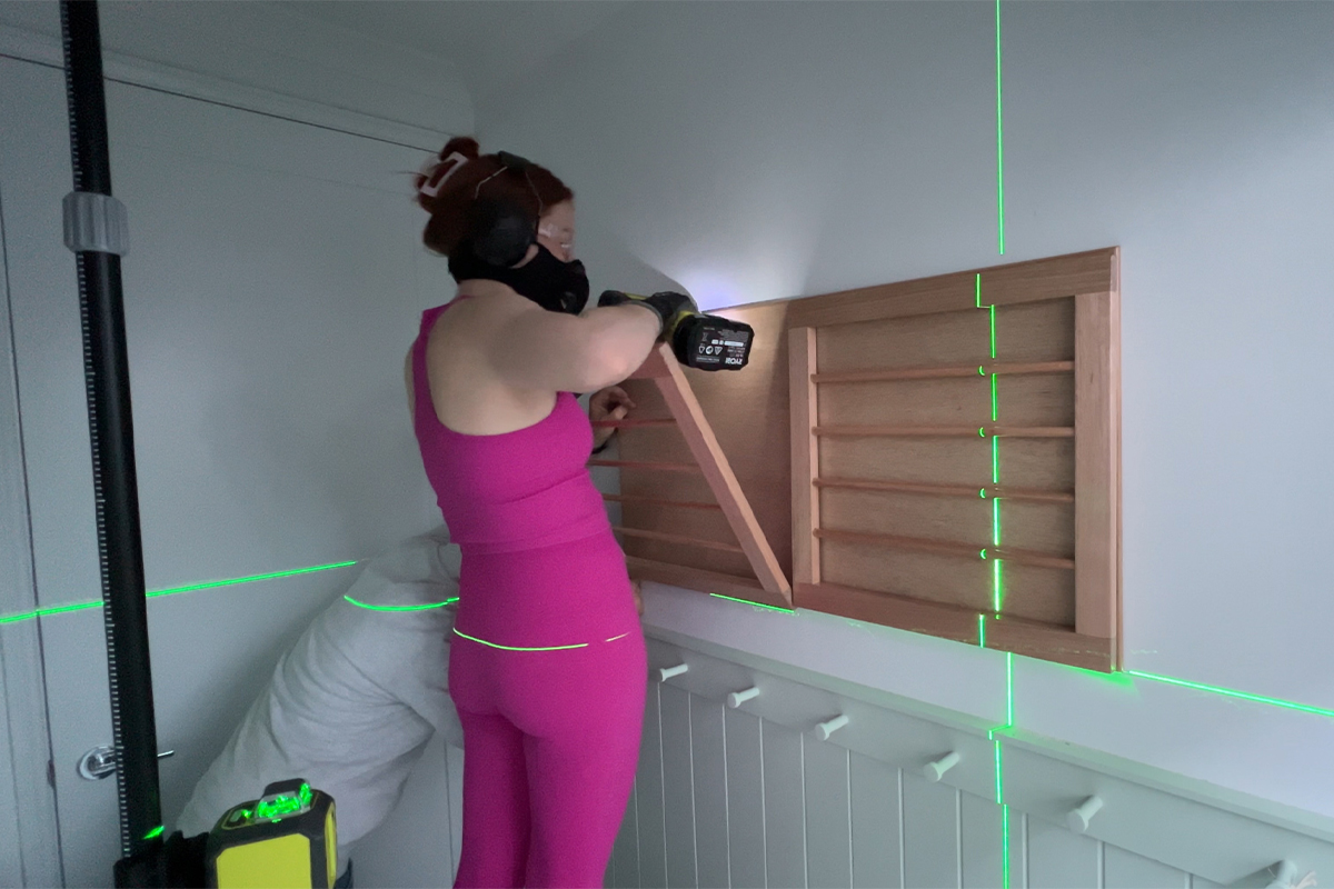 Emma mounts DIY Clothes Rack on wall using RYOBI laser level to ensure straight alignment